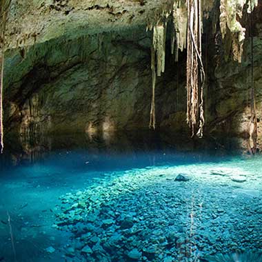 A turquoise pool of water shimmers in a cave. The colour is caused by finely ground minerals suspended in the water.