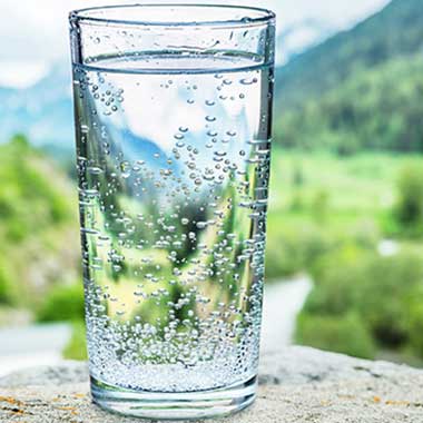 A clear glass of water contains small traces of sodium, typically introduced in water softening. Excess sodium causes negative health effects.